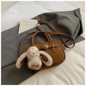 Detailed shot of brown vintage handbag with leather texture and cute plush bunny charm