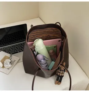 Large dark brown tote bag with striped lining and zip pocket showing high capacity