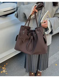 Dettaglio della borsa tote in pelle marrone con chiusura a coulisse e ciondolo a stella