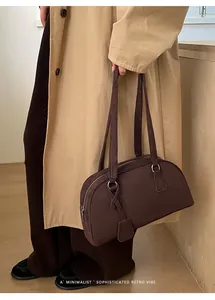 Detail of dark brown suede shoulder bag with dual long handles and minimalist retro vibe
