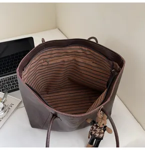 Detail view of large tote bag interior showing striped lining and zip pocket with bear charm