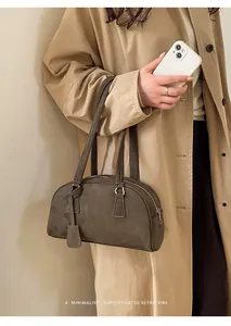 Minimalist brown suede bowling bag styled with a beige trench coat for a chic retro vibe