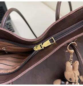 Detailed top view of brown leather tote featuring zipper closure and cute bunny charm