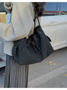 Vista street style di una grande borsa a secchiello nera in pelle con ciondolo a stella
