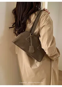 Detail of retro brown suede bowling bag worn on shoulder for a minimalist vibe