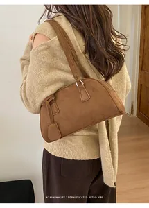 Close-up of brown suede bowling bag worn over shoulder featuring a minimalist retro design