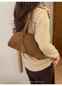Brown faux suede bowling bag shown on shoulder for daily minimalist commute style