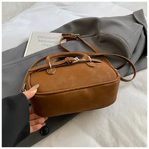 Close-up of brown litchi pattern leather Boston bag with retro strap on a grey blazer