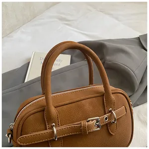 Detail of vintage brown pebble leather handbag with silver buckles and decorative straps