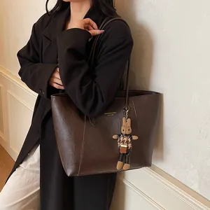 Deep brown large leather tote bag with rabbit charm shown on model in early spring style