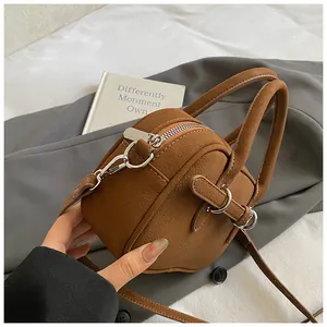 Detailed macro view of small brown lychee pattern leather handbag with silver hardware zippers