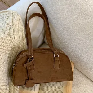 Brown suede bowling bag on white sofa with book in soft aesthetic lifestyle setting