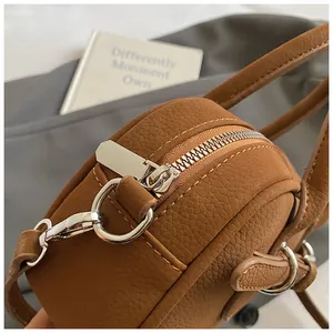 Detail of silver zipper and hardware hooks on brown pebble leather crossbody bag