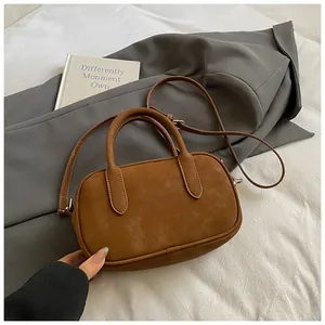 Close-up of caramel brown leather handbag with handles and adjustable shoulder strap