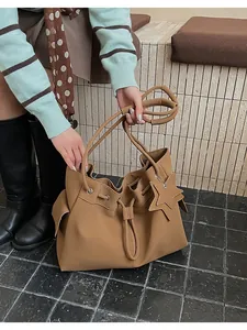 Dettaglio di una borsa tote in pelle marrone con chiusura a coulisse e ciondolo a stella