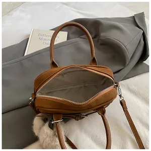 Top view of brown leather handbag interior showing zipper pocket and gray fabric lining