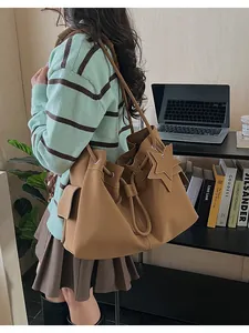 Dettaglio di una borsa tote marrone con coulisse, ciondolo a stella e tasca laterale esterna