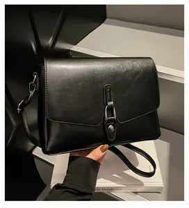 Detail of black crossbody bag featuring silver buckle hardware and smooth matte leather