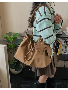 Dettaglio di una borsa a secchiello in ecopelle color cammello con coulisse e stella