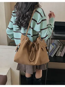 Dettaglio di una grande borsa tote marrone indossata da una modella in un ufficio