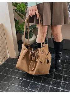 Borsa tote in pelle marrone con ciondolo a stella, indossata da una modella in interni