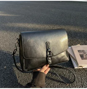 Detailed view of black matte leather crossbody bag with vintage metal buckle and strap