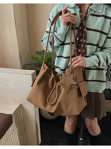 Dettaglio di una grande borsa tote in pelle marrone con ciondolo a stella e tracolla fine