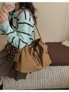Borsa tote in pelle marrone con chiusura a coulisse e tasca laterale su una modella