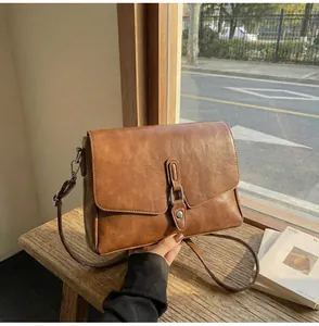 Macro shot of brown faux leather texture and metallic buckle on a vintage crossbody bag