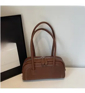 Dettaglio della borsa sottobraccio in pelle marrone con cuciture bianche e doppia zip