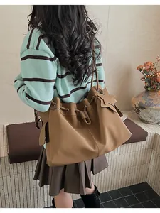 Vista posteriore di una modella con borsa tote marrone a coulisse e ciondolo a stella