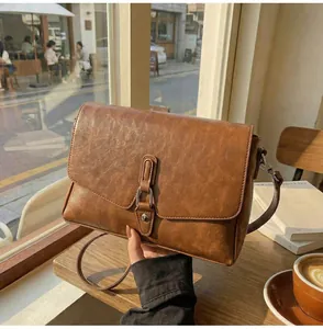 Close-up of vintage brown leather texture and silver buckle on crossbody bag