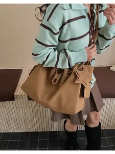 Dettaglio della borsa tote color cammello con ciondolo a stella e finitura testurizzata
