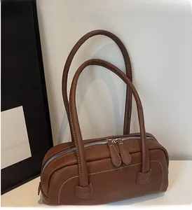 Dettaglio borsa bowling in pelle marrone con doppia zip e cuciture bianche a contrasto