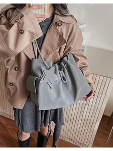 Dettaglio della borsa tote in pelle grigia con design a coulisse e ciondolo a stella