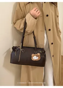 Retro dark brown shoulder bag with striped bow and plush bear charm on khaki trench coat