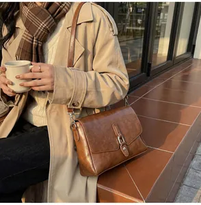 Close-up of retro brown faux leather crossbody bag with flap and silver metal hardware