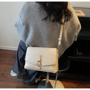 Detailed side view of a beige minimalist square shoulder bag with metal buckle strap