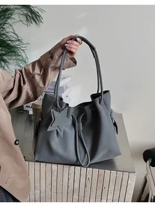 Vista dettagliata della borsa tote in pelle grigia con ciondolo a stella e coulisse nel quotidiano