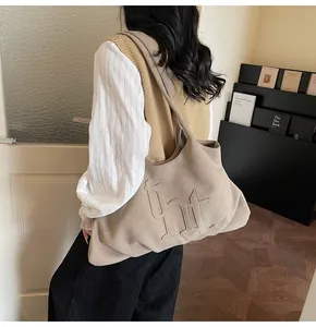 Detail van de grote suède tote bag met THT-letters in reliëf in havermout beige