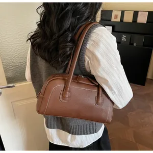 Vista laterale della borsa bowling marrone con cuciture sottili su un modello