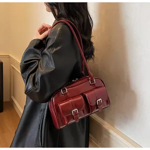 Detail showing the dark red polished leather bag with two buckled front pockets