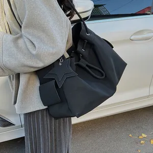 Grande borsa tote in pelle nera con ciondolo a stella e coulisse indossata a spalla