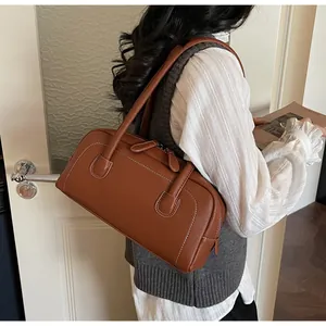 Dettaglio borsa a tracolla in pelle marrone con cuciture bianche a contrasto e design retrò
