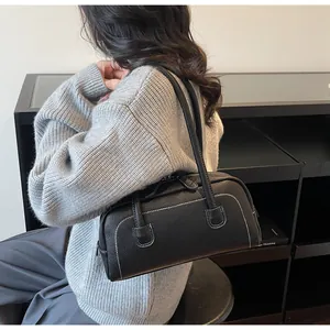 Dettaglio borsa bowling nera in pelle martellata con cuciture a contrasto e tracolla