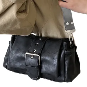 Minimalist black baguette shoulder bag with wide riveted strap and metal buckle detail