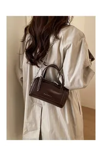 Détail du sac Boston en cuir ciré marron foncé avec chaîne argentée et logo