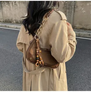 Detail of brown leather moon bag with golden chain strap and vintage beaded tassel