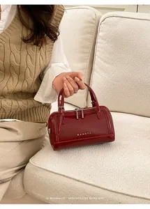Vue détaillée du sac Boston en cuir ciré bordeaux avec logo argenté élégant