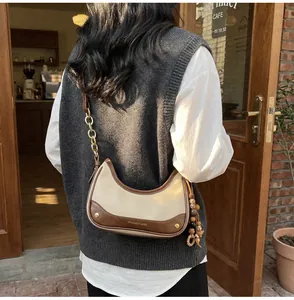 Detail of a retro contrast shoulder bag featuring a half-moon shape and gold chain strap
